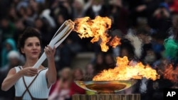 Actress Katerina Lehou playing the role of high priestess lights an Olympic torch during a handover ceremony for the Olympic Flame at Panathenaic stadium in Athens, on Tuesday, Oct. 31, 2017.