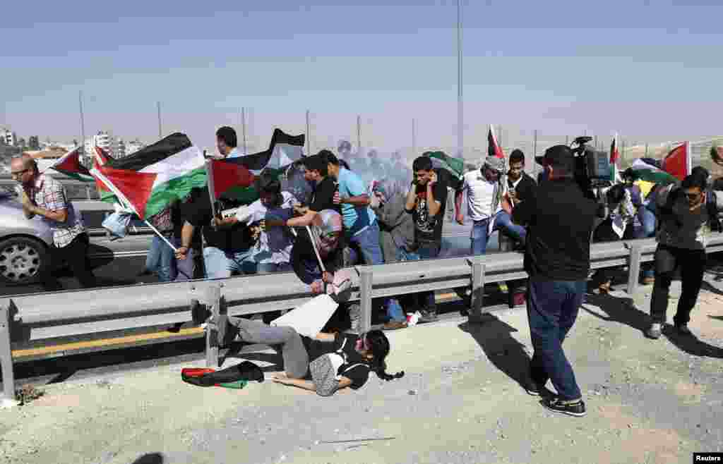 Palestinian protesters run as Israeli border policemen fire a stun grenade duringa demonstration to show solidarity with Bedouin citizens, near the West Bank village of Hizma, south-east of Ramallah August 1, 2013.