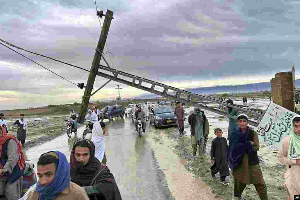 People pass by a damaged electric pole caused by flooding due to heavy rains near Chaman area, Pakistan. Lightning and heavy rains led to 14 deaths in Pakistan, officials said, bringing the death toll from four days of extreme weather to at least 63, as the heaviest downpour in decades flooded villages on the country's southwestern coast.