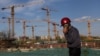Radnik razgovara putem telefonom dok prolazi pored gradilišta u Pekingu, Kina, 14. aprila 2022.