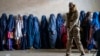 Seorang anggota Taliban berjaga saat kaum perempuan menunggu untuk menerima jatah makanan yang didistribusikan oleh kelompok bantuan kemanusiaan, di Kabul, Afghanistan, 23 Mei 2023. (Foto: AP)