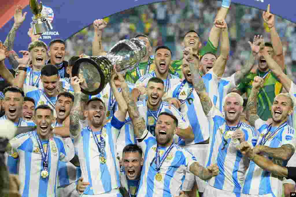 Argentina's Lionel Messi holds the trophy as celebrating with teammates after defeating Colombia in the Copa America final soccer match in Miami Gardens, Florida.