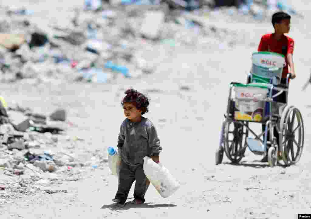 A Palestinian girl carries cans to collect water in Khan Younis, in the southern Gaza Strip.