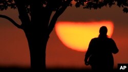 FILE - A woman watches the sun sets on a hot day, Aug. 20, 2023, in Kansas City, Mo. A new study on May 14, 2024, finds that the summer of 2023 was the hottest in the Northern Hemisphere in more than 2,000 years. (AP Photo/Charlie Riedel, File)