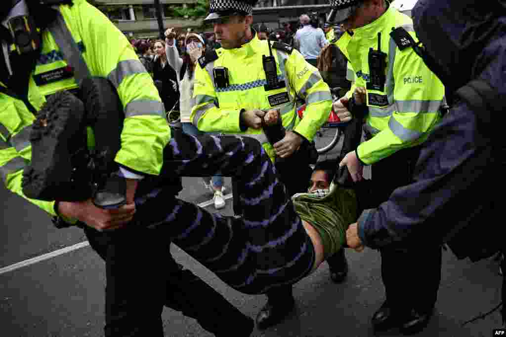 Metropolitan Police officers arrest protesters blocking a bus reportedly waiting to remove migrants and asylum seekers from a hotel in Peckham, south London, to the Bibby Stockholm barge in Portland, Dorset, south-west England.