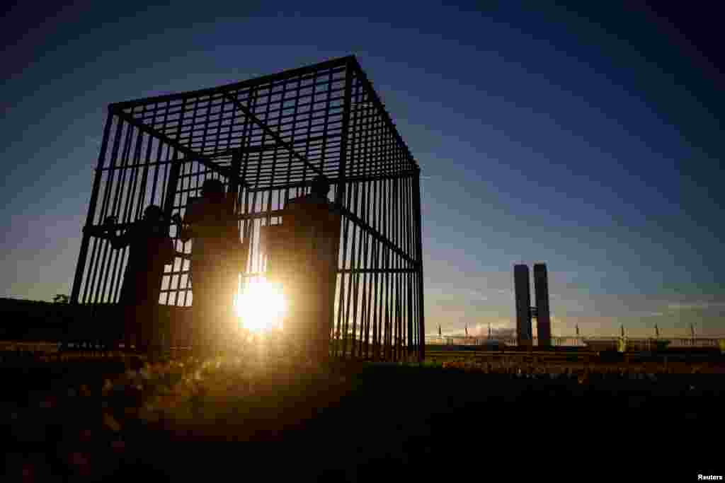 Activists stands in a mock prison cell during a protest against a bill on the possession and use of drugs, in front of the National Congress, in Brasilia, Brazil.
