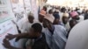 Party agents look at a poster with polling station information in Kano, Nigeria, on Feb. 25, 2023, during Nigeria's presidential and general election. 