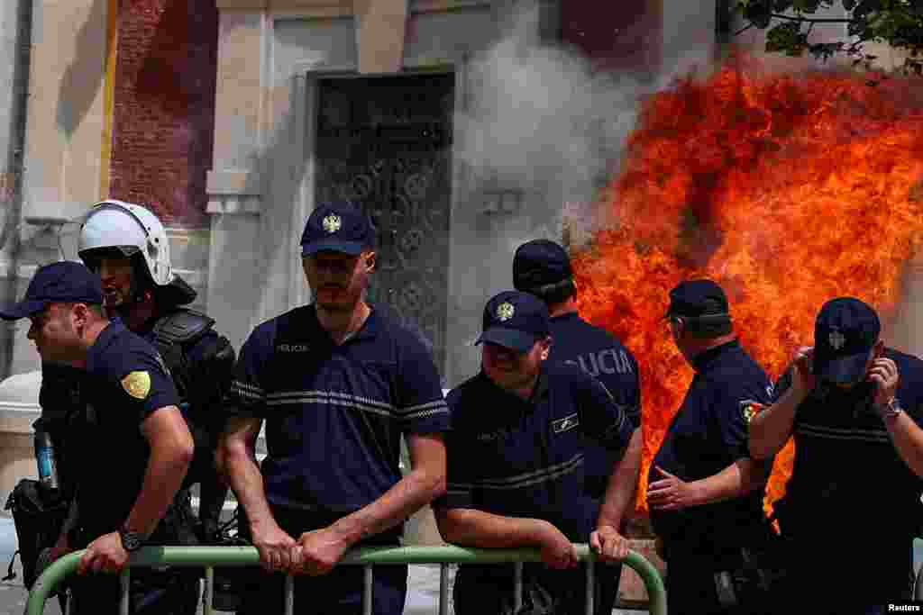 Police officers react as supporters of the opposition hurl Molotov cocktails at the mayor's office accusing him of corruption in Tirana, Albania. 