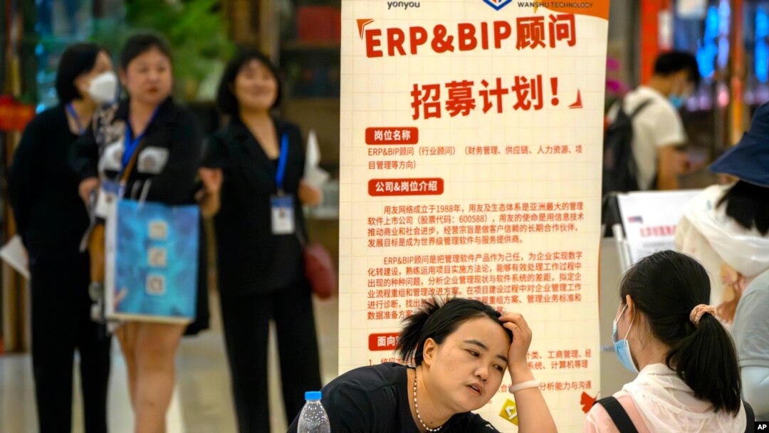 2023年6月9日，一名招聘人員在北京一家購物中心招聘會的展位上與申請人交談。（美聯社照片）
