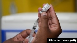 FILE - A healthcare worker prepares the Qdenga vaccine during a vaccination campaign at a health center in Rio de Janeiro, Brazil, Feb. 23, 2024. (AP Photo/Silvia Izquierdo)