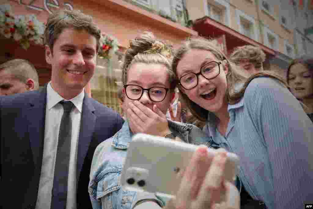 France's Prime Minister Gabriel Attal (C) poses for a selfie with young people during a campaign visit in Le Mans, northwestern France, ahead of the upcoming parliament elections.