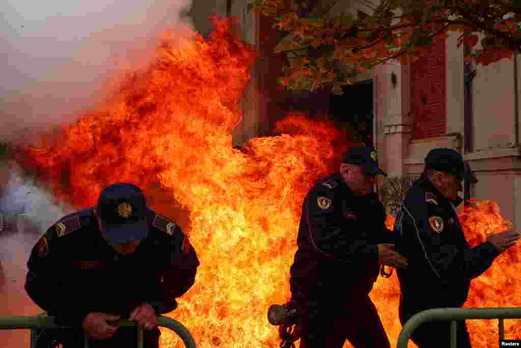 Police officers react as supporters of the opposition hurl Molotov cocktails at the mayor's office, accusing him of corruption, in Tirana, Albania.