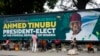 FILE - People sit under a billboard with a congratulatory message of the President-elect Bola Ahmed Tinubu of the All Progressives Congress in Lagos, Nigeria, March 5, 2023. 