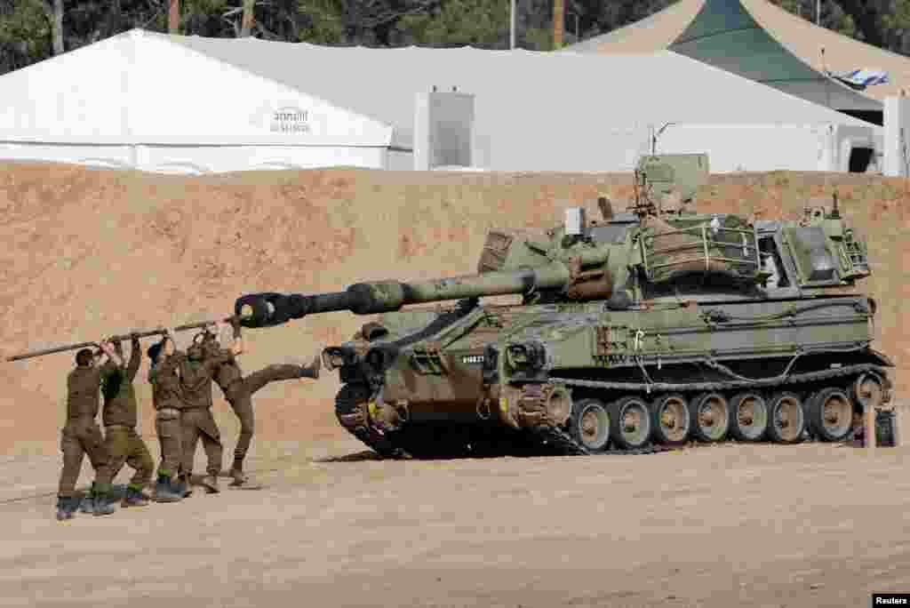 Israeli soldiers clean the barrel of a mobile artillery unit, near the Israel-Gaza border, amid the ongoing conflict between Israel and the Palestinian Islamist group Hamas, in Israel.