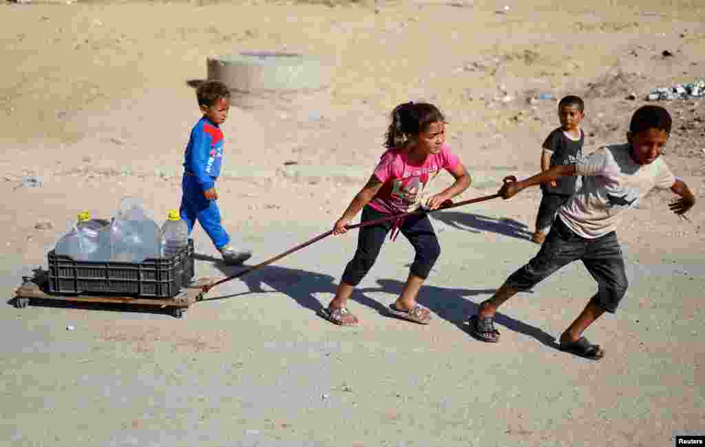 Palestinian children pull water containers after Israeli forces launched a ground and air operation in the eastern part of the southern Gaza city, in the southern Gaza Strip.