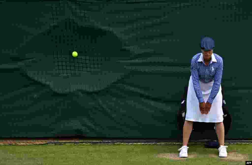 A line judge stands in position as a ball hits the back netting after a serve during the men's doubles semi-final tennis match between Britain's Henry Patten and Finland's Harri Heliövaara, and New Zealand's Michael Venus and Britain's Neal Skupski, during the Wimbledon Championships in Wimbledon, southwest London. 