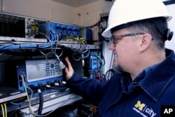 This photo from the University of Michigan shows tester Jim Lollar working inside a traffic control cabinet at the Mcity Test Facility. (Jeremy Little/University of Michigan College of Engineering via AP)