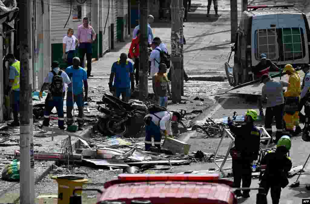 Police officers and civilians inspect the scene of the explosion in Jamundi, Valle del Cauca province, Colombia. The explosion left at least two police officers injured according to local authorities.
