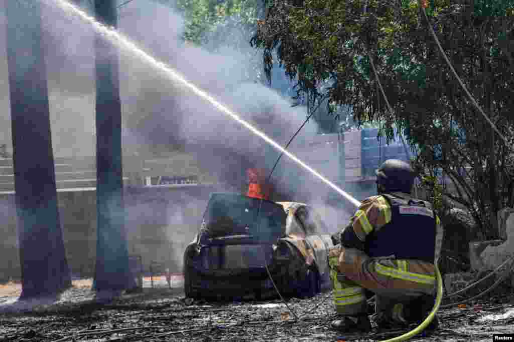 A firefighter puts out a fire at the site of a rocket that was fired towards Israel from Lebanon, in Kiryat Shmona, northern Israel, amid ongoing cross-border hostilities between Hezbollah and Israeli forces.