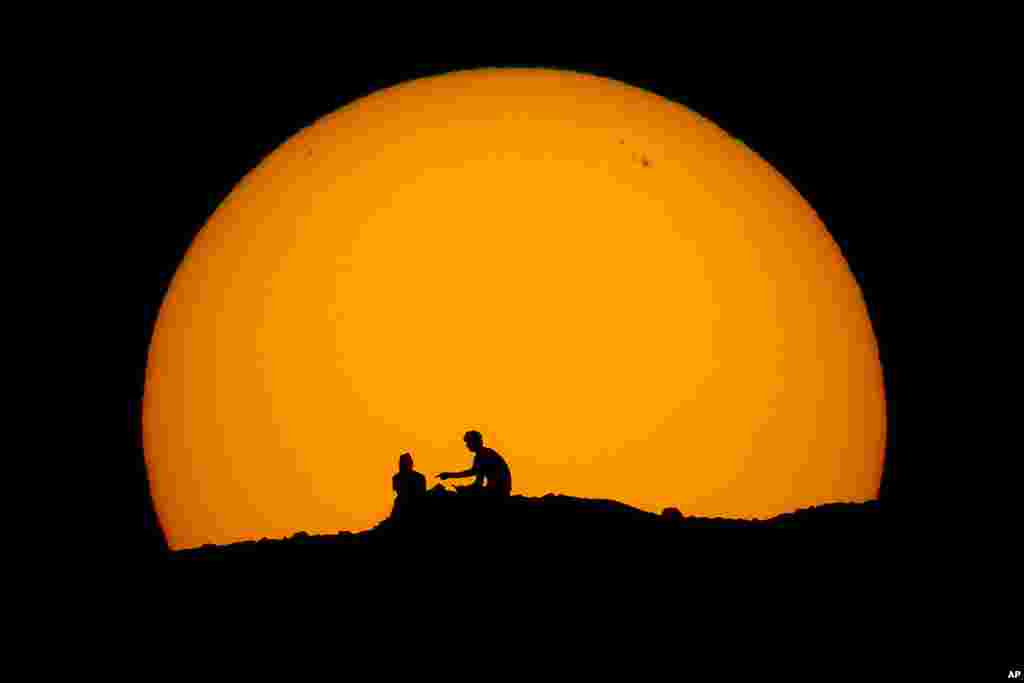 Hikers are silhouetted against the setting sun at Papago park, Feb. 18, 2023, in Phoenix, Arizona. 