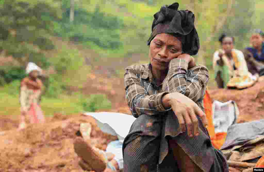 Zeritu Zekarias, 43, sits on the ground as her husband and relatives dig in search of the missing son at the site of the twin landslides of July 22, 2024, following heavy rains, in Gofa zone, Geze District of Southern Ethiopia, July 29, 2024.