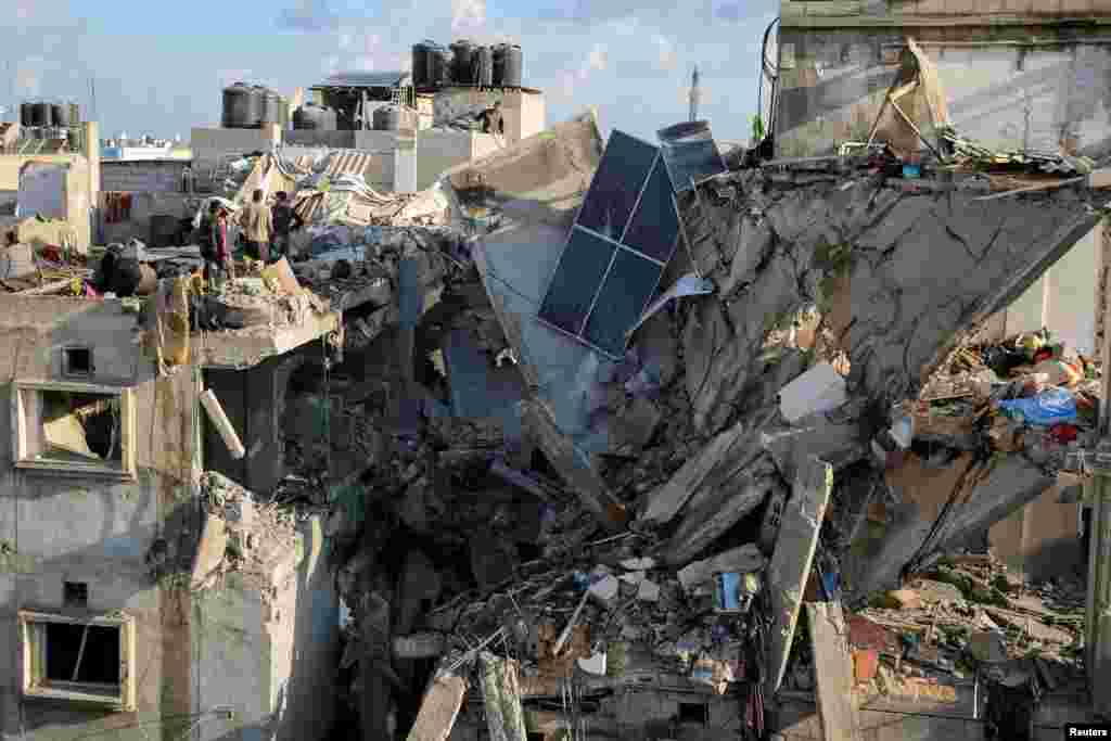 Palestinians inspect the site of an Israeli strike on a house, amid the ongoing conflict between Israel and the Palestinian Islamist group Hamas, in Rafah, in the southern Gaza Strip.