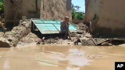 আফগানিস্তানের বাঘলান প্রদেশে ভারী বন্যার পরে একজন ব্যক্তি তার ক্ষতিগ্রস্ত বাড়ির সামনে বসে আছেন। ১২ মে, ২০২৪। 