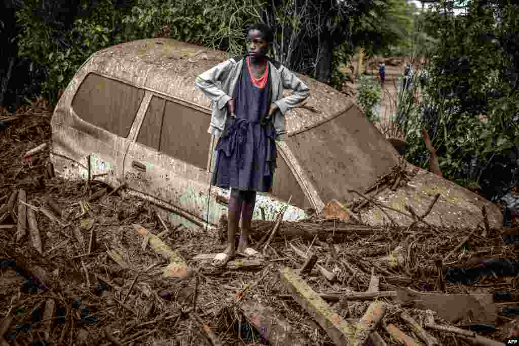 A girl looks on next to a damaged car buried in mud in an area heavily affected by torrential rains and flash floods in the village of Kamuchiri, near Mai Mahiu, Kenya. At least 45 people died when a dam burst its banks near a town in Rift Valley, police said, as torrential rains and floods battered the country. 