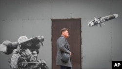 Un ciudadano camina frente a un grafiti que ilustra a un soldado ucraniano disparando un proyectil anti-tanques, en las calles de Kiev, el 24 de octubre de 2022.
