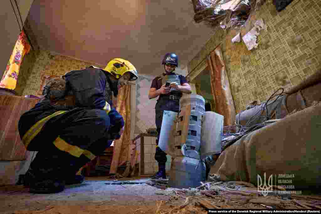 Ukraine's State Emergency Service members inspect an unexploded shell from a Smerch multiple launch rocket system inside a residential apartment in Kramatorsk as Russia's attack on Ukraine continues.