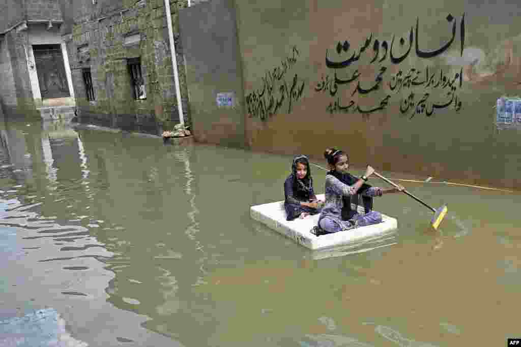 Girls use a temporary raft to cross a flooded street in a residential area after heavy monsoon rains in Karachi, Pakistan.
