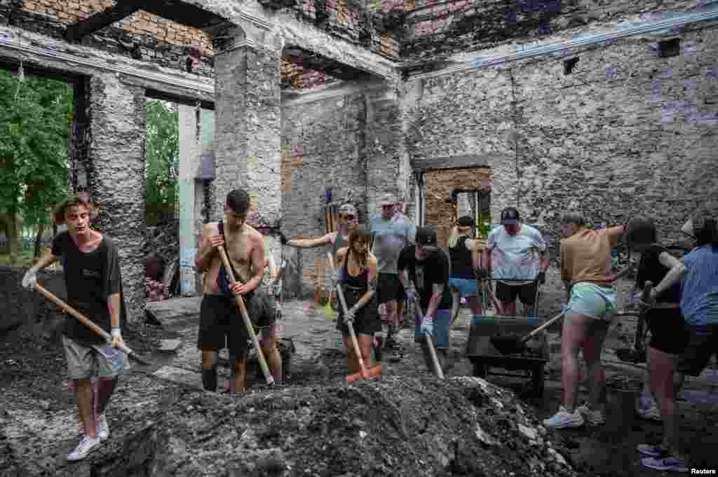 Volunteers clean up the House of a Culture in the village of Yahidne, which was heavily damaged during Russia's attack on Ukraine, in Chernihiv region, Ukraine, July 23, 2022. 