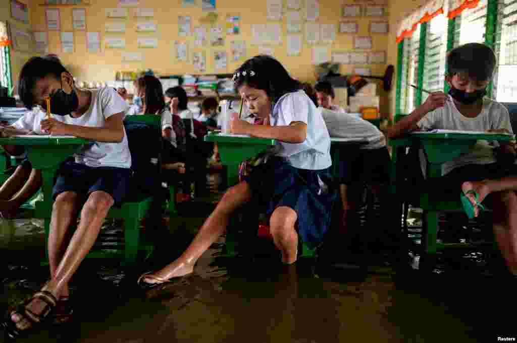 Students attend the first day of in-person classes, at a flooded school in Macabebe, Pampanga province, Philippines.