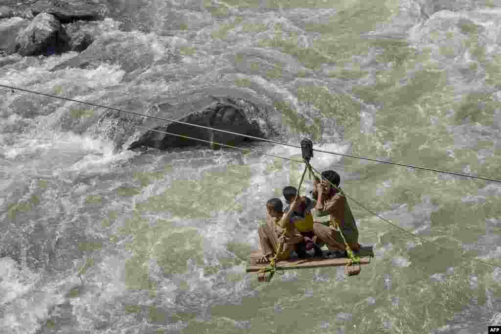 Local residents use a temporary cradle service to cross the river Swat after heavy rains in Bahrain town of Swat valley in Khyber Pakhtunkhwa province, Pakistan.