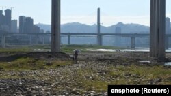 一名女子走過因乾旱而裸露在外的重慶段長江河床。（2022年8月17日）
