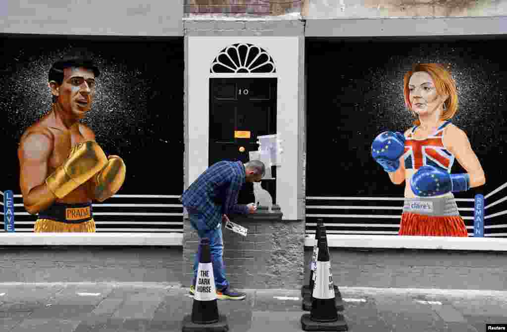 Artist Ciaran Gallagher finishes his mural depicting Britain's Conservative leadership candidate Rishi Sunak and British Foreign Secretary and Conservative leadership candidate Liz Truss, by painting Larry the cat, in the city center of Belfast, Northern Ireland.