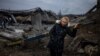 A woman rests after crossing a destroyed bridge as she evacuates from the city of Irpin, northwest of Kyiv, on March 7, 2022.