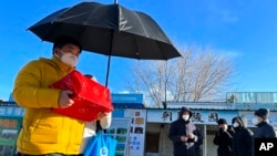 美聯社2022年12月17日照片上一名男子手捧親人骨灰盒走出一家北京火葬場。中國民政部在2023年6月9日公佈的去年四季度民政統計數據中獨缺遺體火化數目。