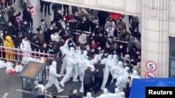 Wakazi wa Shanghai wakabiliana na wafanyakazi wa kudhibiti virusi vya corona waliovalia nguo za kujikinga na maambukizi huko Shanghai, China katika hii picha iliyopatikana kutoka katika video ya mitandao ya kijamii iliyotolewa Nov. 30, 2022. Kanda ya video iliyowafikia Reuters.