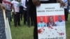 FILE - A protester holds a sign picturing human rights attorney Willie Kimani, his client Josephat Mwenda and their taxi driver Joseph Muiruri allegedly killed by police, at a rally in Nairobi, Kenya, July 4, 2016. (J. Craig/VOA)