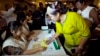 A volunteer clad in Shan ethnic traditional costume fills in a ballot paper during a rehearsal presentation for the upcoming general election Friday, May 15, 2015, in Yangon, Myanmar. (AP Photo/Khin Maung Win)