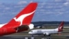 FILE - Two Qantas passenger jets sit on the tarmac and runway at Sydney International Airport, in Sydney, Australia, July 27, 2000.