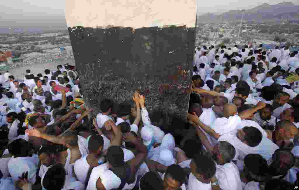 Muslim pilgrims pray on a rocky hill called the Mountain of Mercy, some touching a marker at its peak, on the Plain of Arafat, near the holy city of Mecca, Saudi Arabia, Oct. 14, 2013.