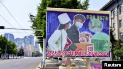 朝鲜平壤空荡荡的街道和路旁竖立的新冠防疫宣传画。（2022年5月23日）