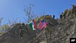 2022年11月30日，印度和美国陆军士兵举着各自国家的国旗，在印美联合演习期间跑上一座小山。 (美联社照片）