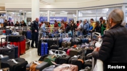 Para penumpang maskapai Southwest Airlines antre untuk memeriksa bagasi mereka dari penerbangan yang dibatalkan di Bandara Internasional Midway Chicago, Selasa 27 Desember 2022.