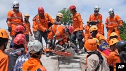Wafanyakazi wa uokoaji wkaitumia msomeno kufikia mwili wa muhanga wa tetemeko la ardhi aliyekuwa chini ya kifusi katika mji wa Cianjur, magharibi ya Java, Indonesia, Nov. 22, 2022. 
