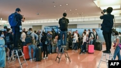 資料照：日本因新冠疫情邊控外國遊客來日本觀光旅遊兩年半後，於2022年10月首次開放。新聞記者站在梯子上為抵達日本羽田國際機場的外國遊客拍照。 （2022年10月11日）