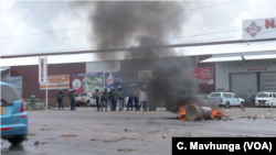 Zimbabwe’s police watch tires burning as protesters try to block a road in Harare during (January 2019) protests over a 150 percent fuel increase.
