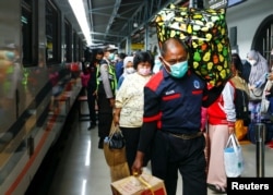 Penumpang membawa barang bawaan mereka saat berjalan di stasiun kereta api untuk mudik menjelang perayaan Idul Fitri, di tengah pandemi COVID-19, di Jakarta, 5 Mei 2021. (REUTERS/Ajeng Dinar Ulfiana)
